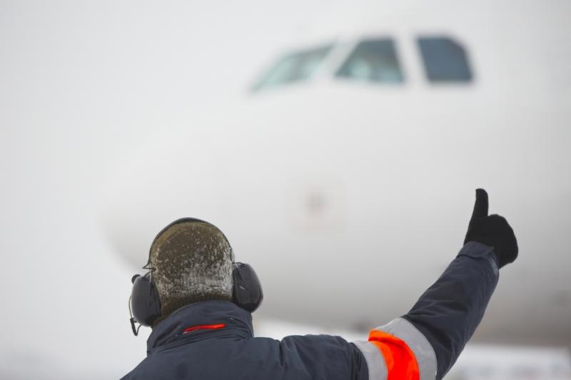 Workers at an airport wearing earmuffs with Push to Talk