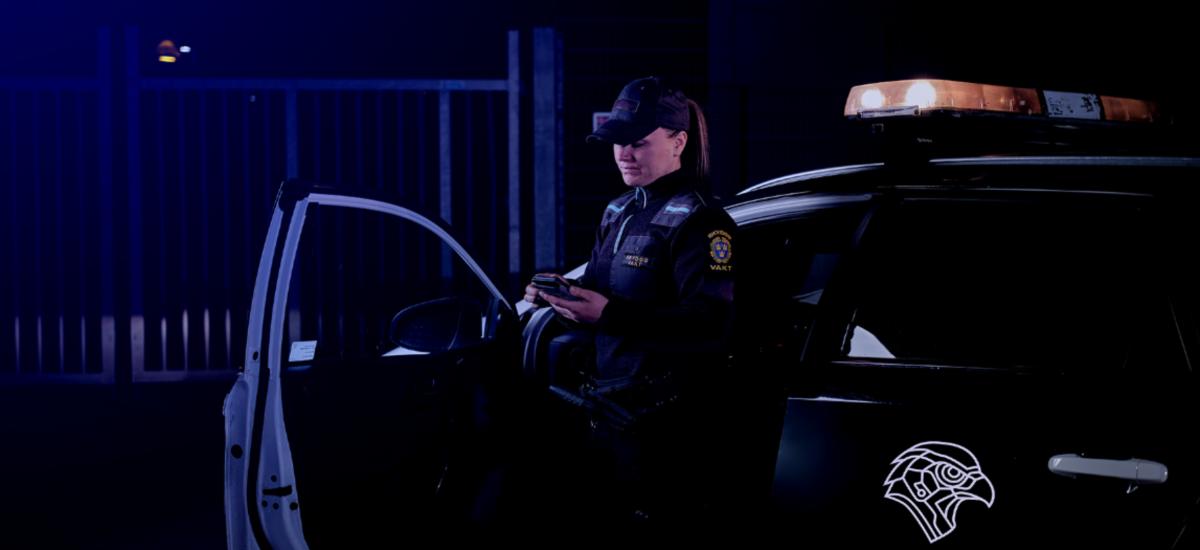 Security guard standing by car using smartphone.