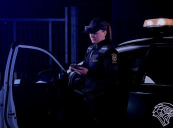 Security guard standing by car using smartphone.