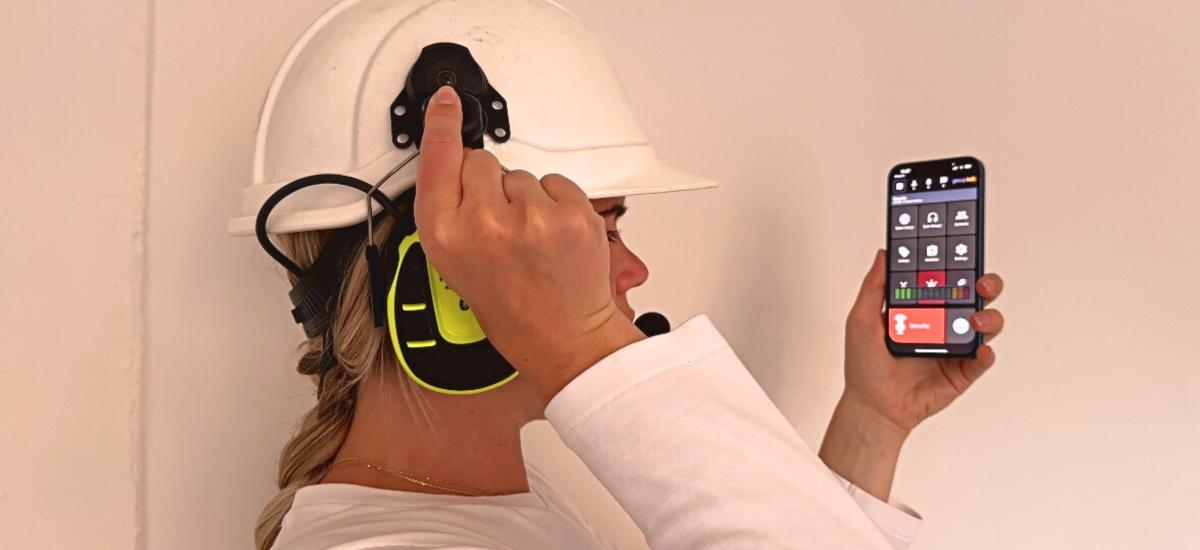 Girl wearing a helmet with earmuffs attached and talking in the GroupTalk walkie talkie app.