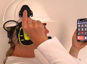 Girl wearing a helmet with earmuffs attached and talking in the GroupTalk walkie talkie app.