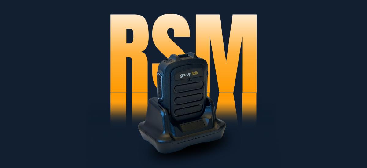 Bluetooth push-to-talk microphone docked in desktop charger.