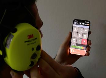 Man using GroupTalk PTT app on iPhone with 3M Peltor headset.