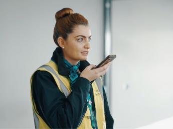 Airport worker talking to her colleagues using a two way radio app