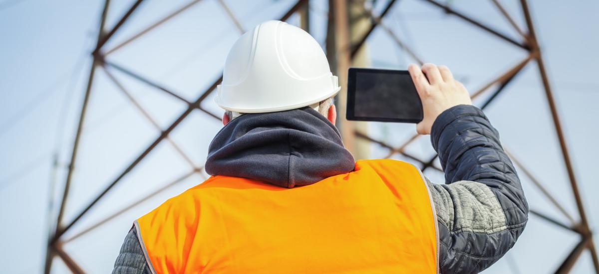 Electrical engineer filmed with tablet PC high voltage tower.