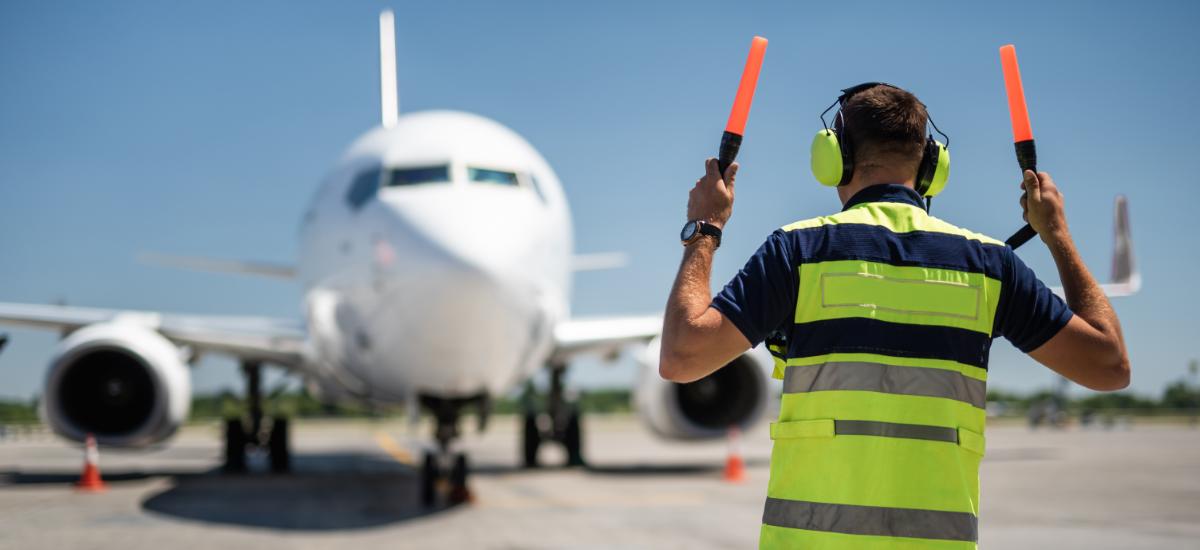 Airport worker with Peltor PTT headset at gate.