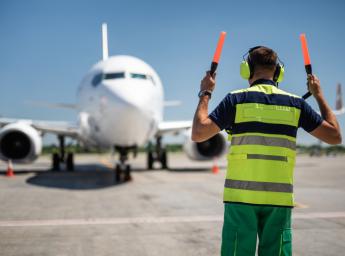 Ground handling worker helping a pilot parking the aircraft at the gate.