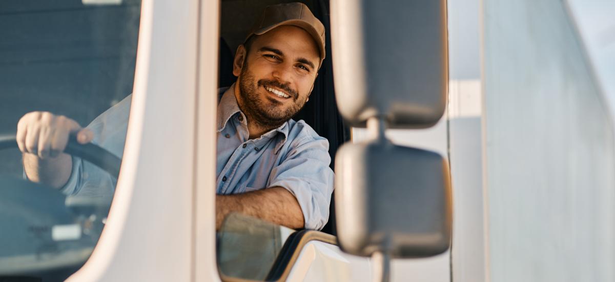 Man smiling at camera while driving a truck.