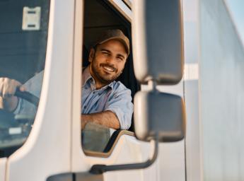 Happy truck driver looking through side window while driving his truck.