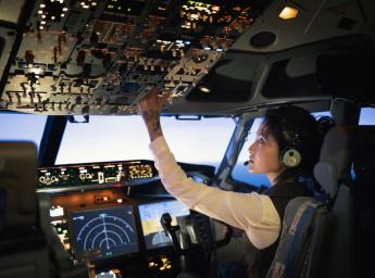 Female pilot operating controls in cockpit.