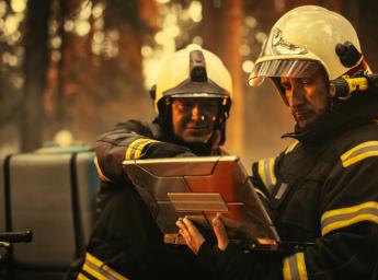 Professional firefighters coordinating wildfire response with laptop.
