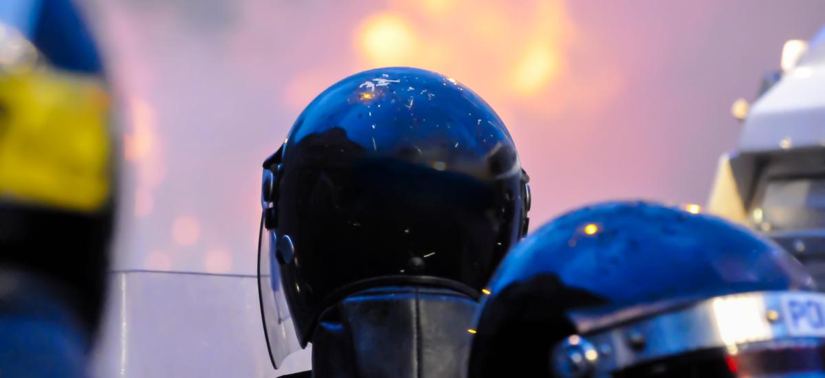 Police officers observing crowd rioting and van on fire in Belfast.