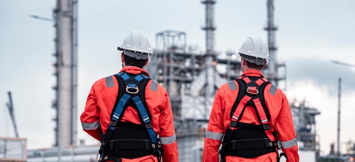 Oil rig workers wearing ATEX safety equipment in hazardous environment.