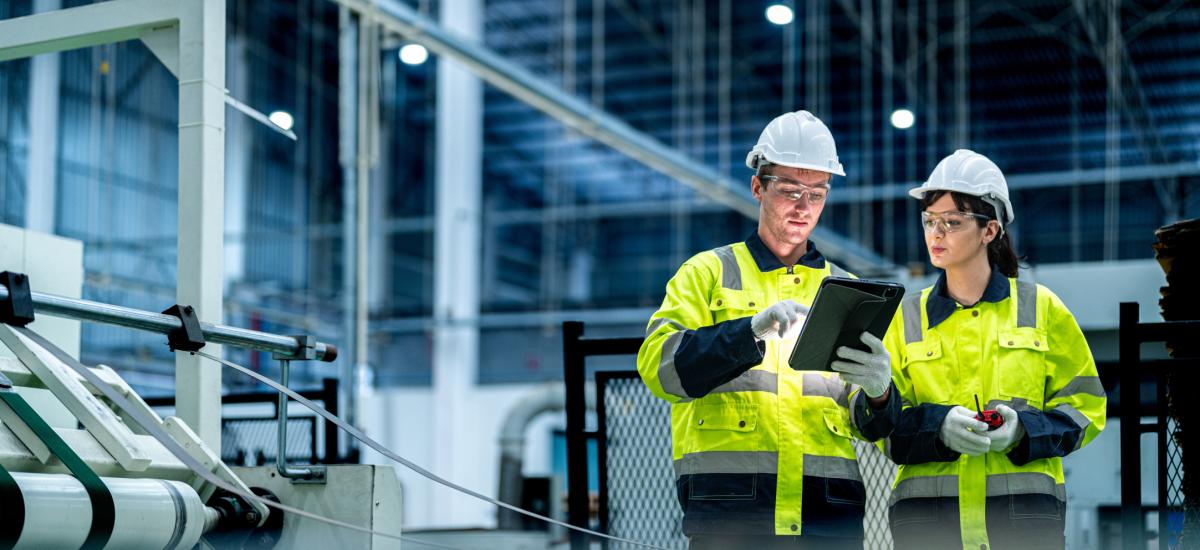 Male and female engineers managing factory machines.