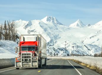Freight truck transporting goods through Alaska wilderness.