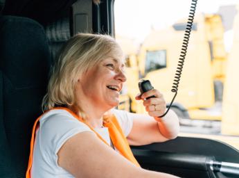 Truck driver communicating via RSM with PTT buttons while smiling.