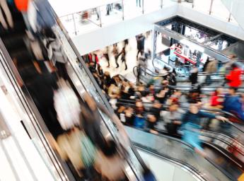 Crowded shopping mall with many people on an escalator.