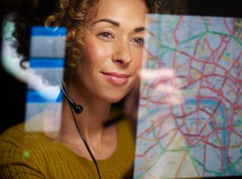 Woman monitoring map on computer with push-to-talk headset.
