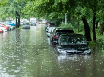 Flooding and cars parked on a street covered in water.