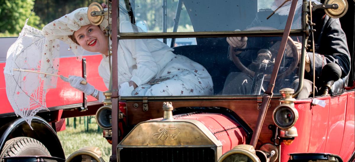 A male and female sitting in an old car at the TimeWinder event.