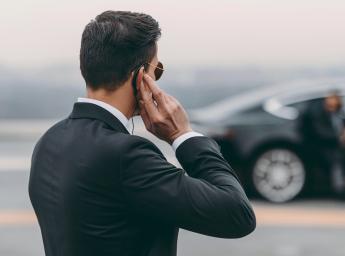 Undercover guard using push-to-talk headset to communicate with team.