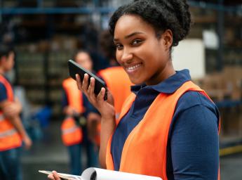 Logistics worker using smartphone with 5G for push-to-talk.